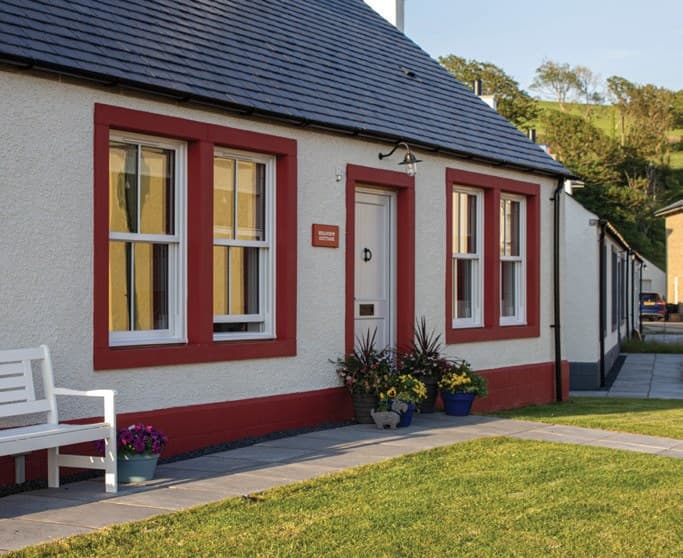 Sliding sash windows sprayed in a deep red, set in a white rendered cottage
